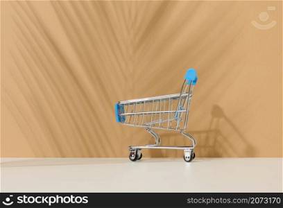 empty miniature shopping cart on brown background. Seasonal sale, copy space, online shopping