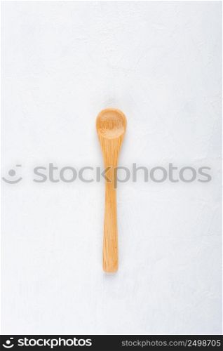 Empty new clean small bamboo wooden spoon on white table background top view flat lay.
