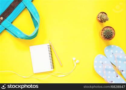 Empty notebook, earphones, cactus with woman items on yellow background with copy space
