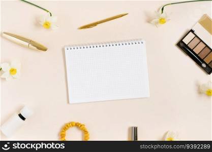 Empty notepad sheet with a copy space surrounded by women’s decorative cosmetics and narcissus flowers. Flat lay