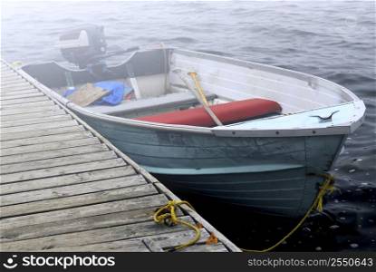 Empty old boat at a dock on a misty lake