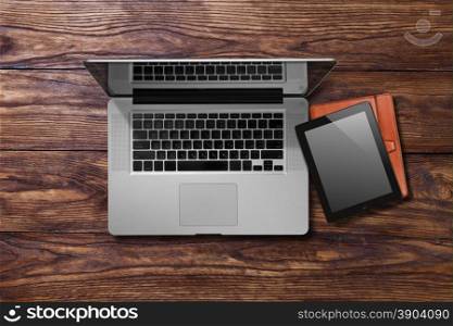 empty old brown wooden background. Open laptop and tablet pc on brown wooden table. Top view