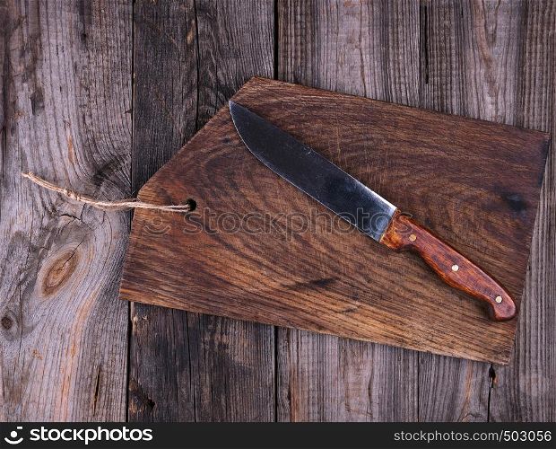 empty old brown wooden cutting board and knife on the table, top view