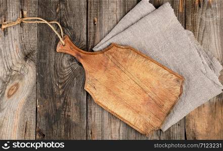 empty old brown wooden cutting board with handle and gray textile napkin, top view