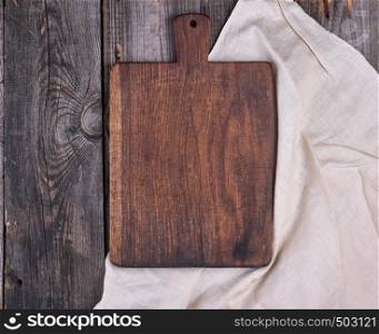 empty old brown wooden cutting board with handle and white textile napkin, top view