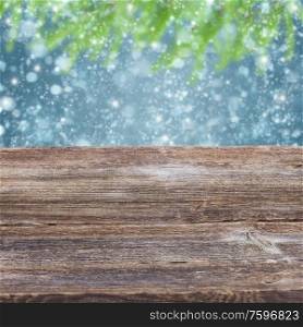 empty old wooden table with snowfall and fir tree bokeh background. wooden planks with golden bokeh background