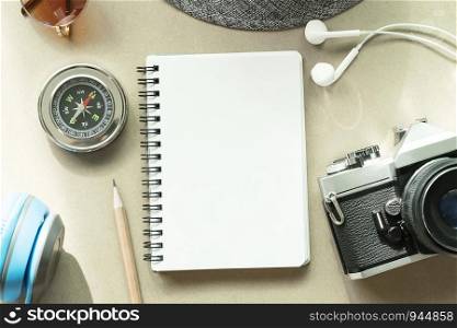 Empty opened white page of notebook with pencil, camera, compass and accessories on table. Travel background concept.