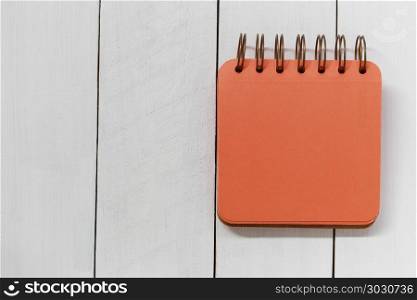 Empty orange notebook on white wooden floor.. Empty orange notebook on white wooden floor and have copy space to design in your work.