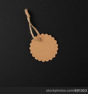 empty paper round brown tag on a rope, black background, sales concept