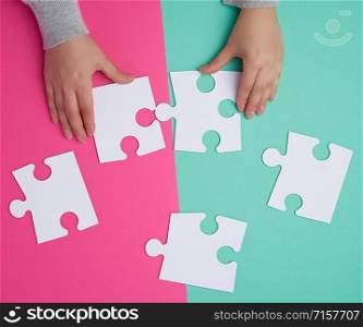 empty paper white pieces of puzzles in female hands, puzzle connected, colorful background, top view