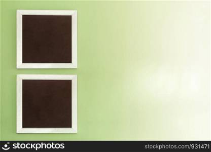 Empty photo frames on green wall with free space background.