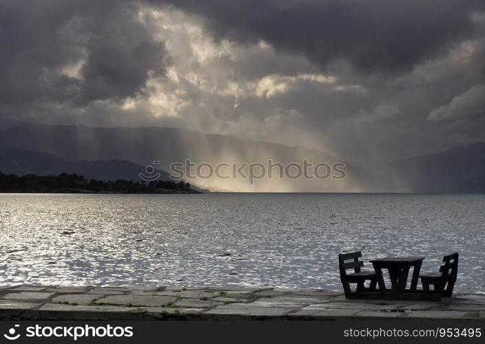 Empty picnic table in in the Norwegian village Herand in front of a dramatic sky over the Hardangerfjord. Empty picnic table in Herand