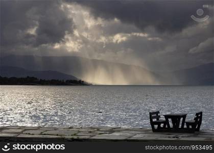 Empty picnic table in in the Norwegian village Herand in front of a dramatic sky over the Hardangerfjord. Empty picnic table in Herand