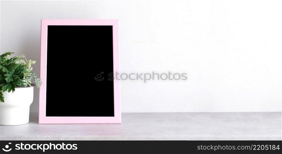 Empty pink wooden frame standing over white cement wall and black marble floor with shadow background, copy space for mock up and template