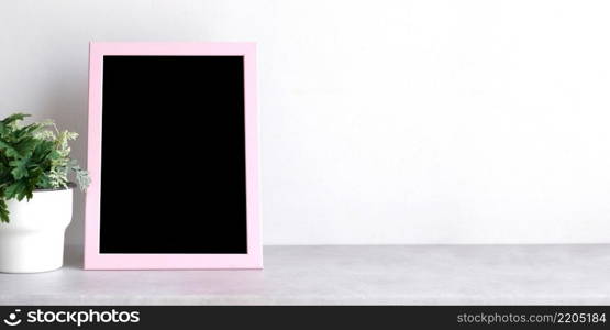 Empty pink wooden frame standing over white cement wall and black marble floor with shadow background, copy space for mock up and template