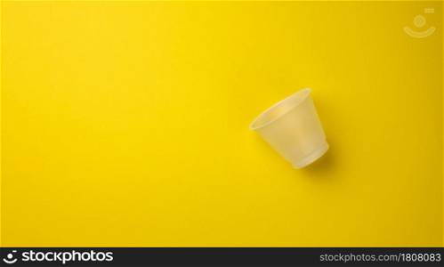 empty plastic cup on yellow background, top view
