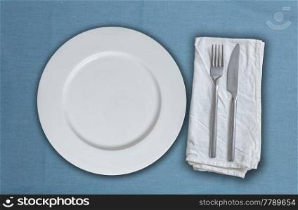 Empty plate and cutlery on blue cloth.. Empty plate and cutlery on blue cloth