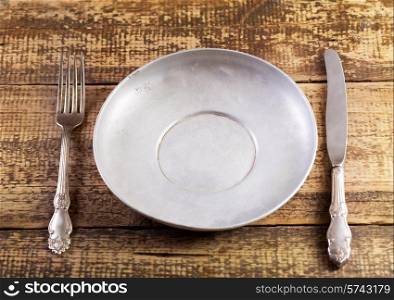 empty plate fork and knife on wooden table