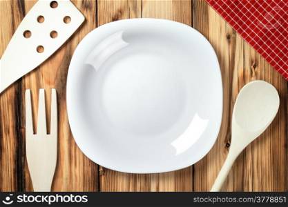 Empty plate on table background. Wooden cutlery and napkin. Top view