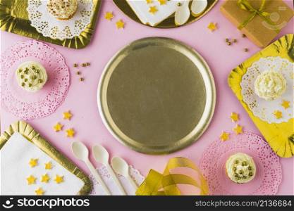 empty plate surrounded with muffins decorative pink background
