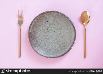 Empty plate, Table setting. Ceramic plate, spoon and fork on pink pastel colour background