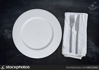 Empty plate with cutlery on blackboard background.. Empty plate with cutlery on blackboard background