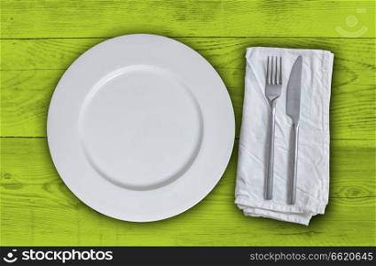 Empty plate with cutlery on light green vintage wood.. Empty plate with cutlery on light green vintage wood