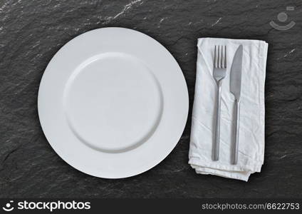 Empty plate with cutlery on slate background.. Empty plate with cutlery on slate background