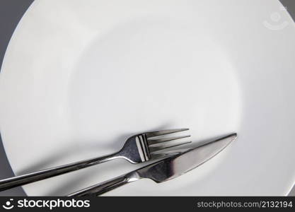 Empty plate with fork and knife on gray background, top view for copy space, food and healthy eating concept space for text. Empty plate with fork and knife on gray background, top view for copy space, food and healthy eating concept