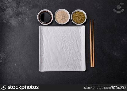 Empty plate with wooden sticks for Asian food on a dark concrete background. Preparation of Asian cuisine. Empty plate with wooden sticks for Asian food on a dark concrete background