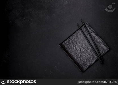 Empty plate with wooden sticks for Asian food on a dark concrete background. Preparation of Asian cuisine. Empty plate with wooden sticks for Asian food on a dark concrete background