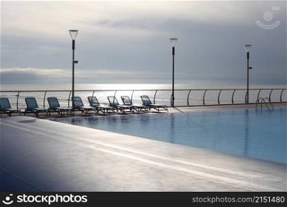 Empty recreation area with pool and beach lounger near the sea. Evening nature calm landscape.