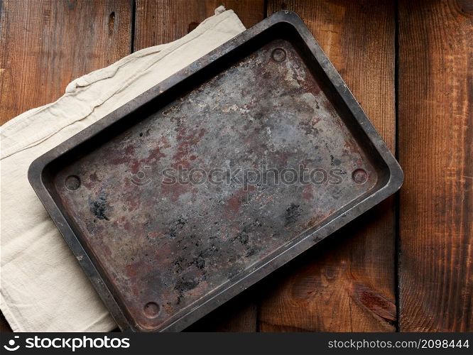 empty rectangular iron rusty baking sheet on a wooden brown table, top view