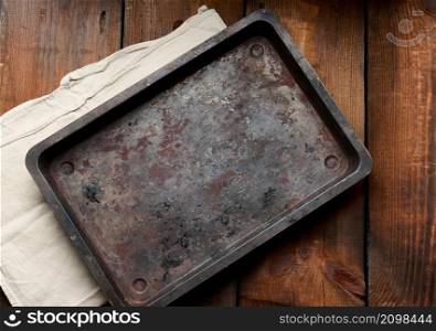 empty rectangular iron rusty baking sheet on a wooden brown table, top view