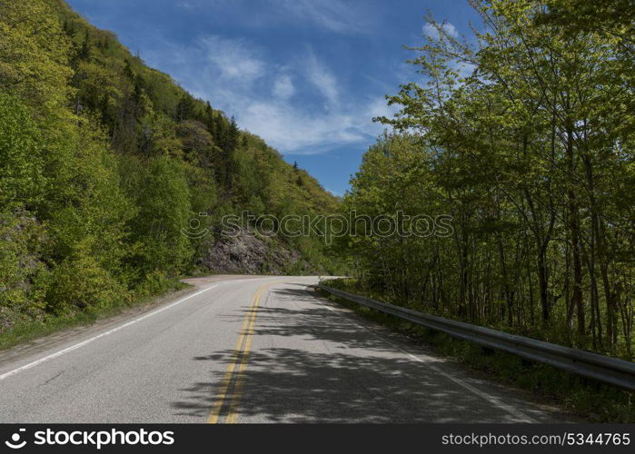 Empty road amidst trees by hills, Dingwall, Cabot Trail, Cape Breton Highlands National Park, Cape Breton Island, Nova Scotia, Canada