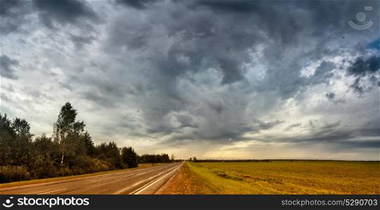 Empty road in cloudy rainy autumn day panorama. Wet road landscape under cloudy sky.
