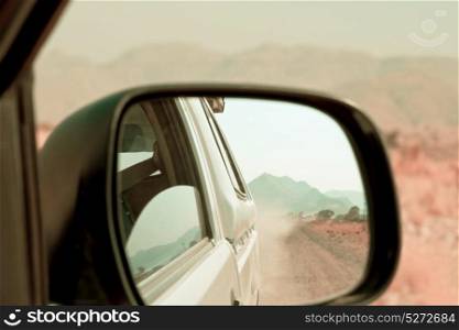 empty road in the african desert - view in the car mirror