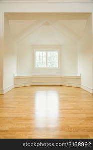 Empty room in house with sunlight coming through window on hardwood floors.