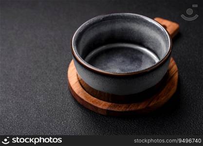 Empty round ceramic bowl on a wooden cutting board in brown color on a dark textured concrete background