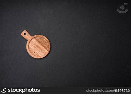 Empty round kitchen wooden cutting board in brown color on a dark textured concrete background
