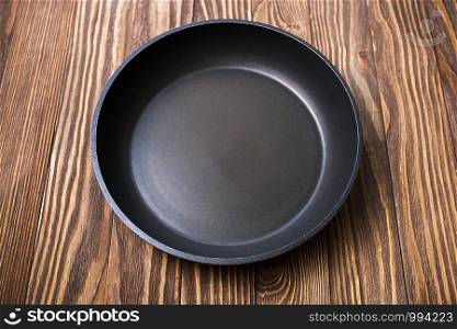 Empty round pan for cooking on wooden background, selective focus, top view.. Empty round pan for cooking on wooden background, selective focus, top view
