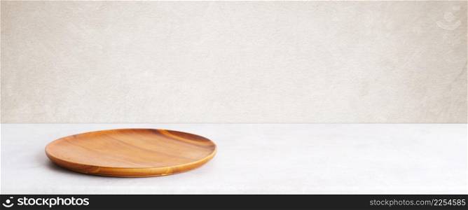 Empty round wooden plate on white cement table and brown cement wall background, Blank wood tray banner for food display montage, template, mock up