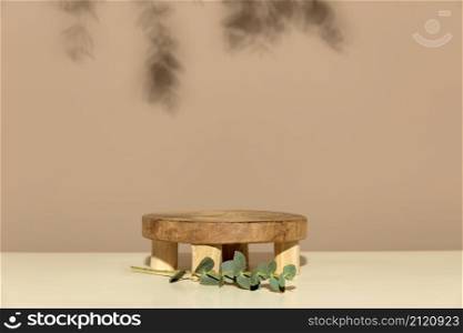 Empty round wooden podium for product presentation eucalyptus leaves on beige background abstract background. Minimal box and geometric podium. Scene with geometrical forms. Empty showcase for eco cosmetic product presentation
