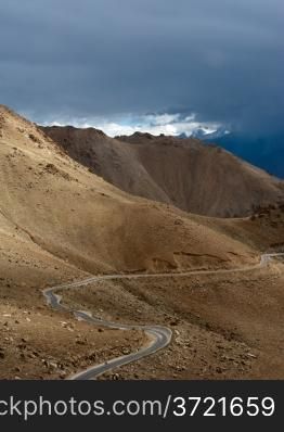 Empty rural road going through Himalaya high mountain landscape panorama with dramatic cloudy sky. India, Ladakh