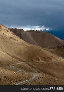Empty rural road going through Himalaya high mountain landscape panorama with dramatic cloudy sky. India, Ladakh