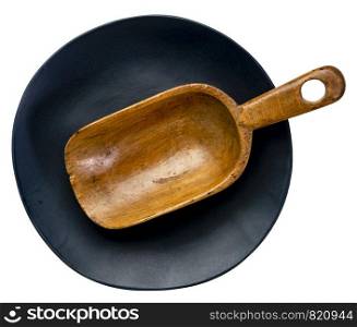 empty rustic wooden scoop on a black ceramic plate with an irregular edge isolated on white