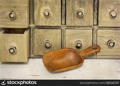 empty rustic wooden scoop with a primitive apothecary drawing cabinet in a background