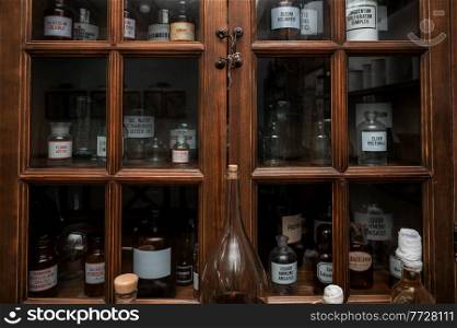 Empty scent bottles in old pharmacy. Wooden antique cupboard for medical drug storage. Empty scent bottles in old pharmacy
