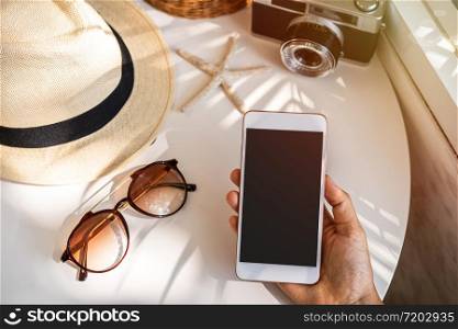 Empty screen smart phone with travel accessories on the table, Summer vacation concept