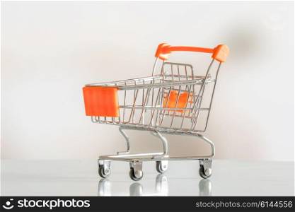 Empty shopping cart in orange color in a market